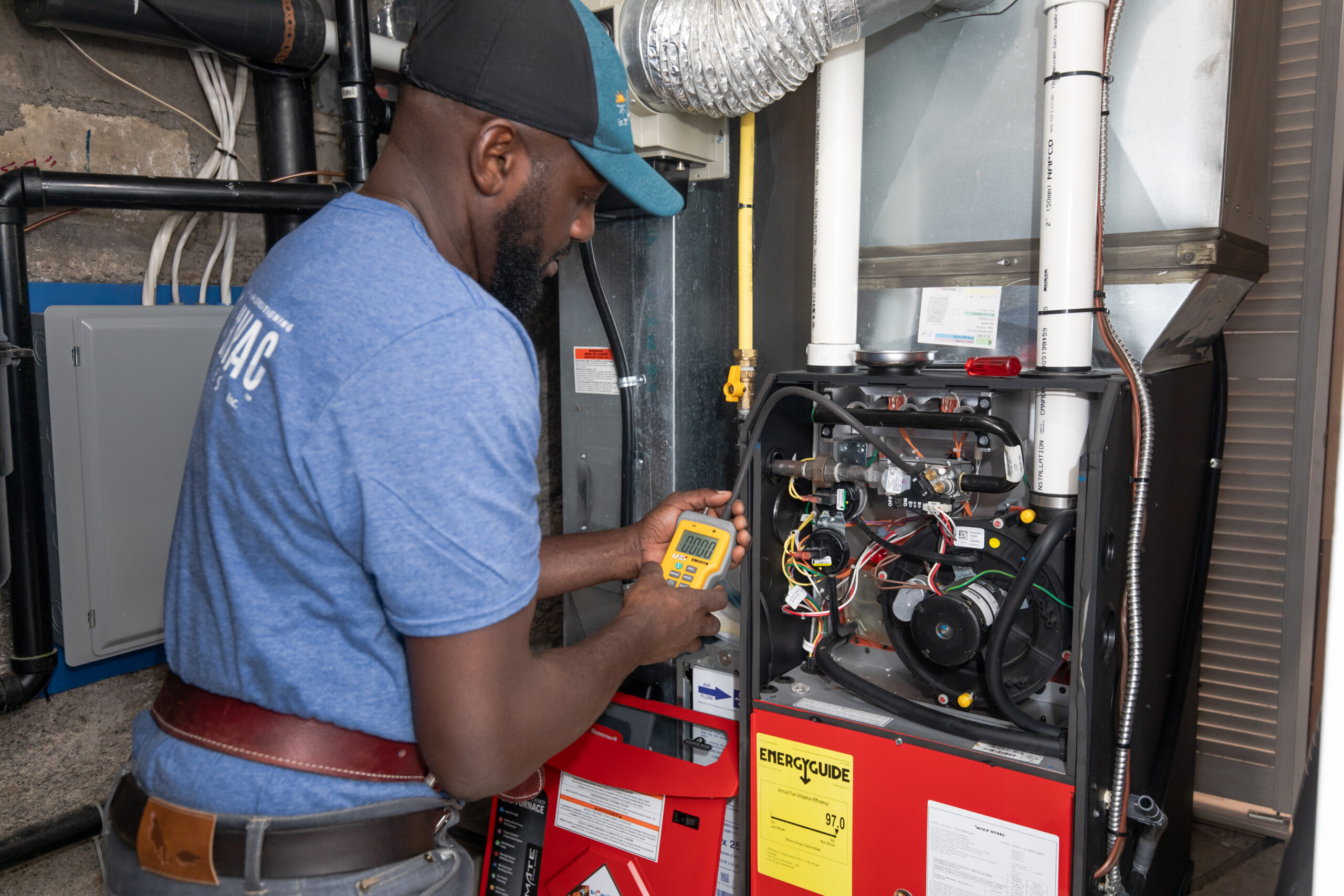 A Lloyd HVAC technician testing a furnace with a meter - a clear example of why HVAC maintenance matters